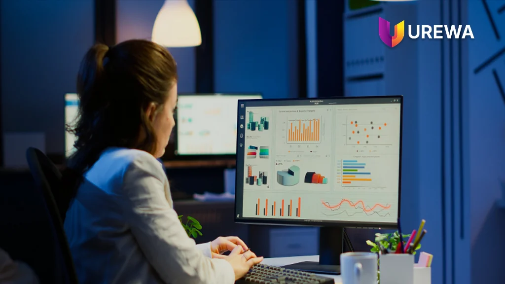 A finance analyst reviewing a Power BI dashboard on a desktop monitor, with revenue projections, scatter analysis, category comparisons and trend charts drawn from Dynamics 365 data